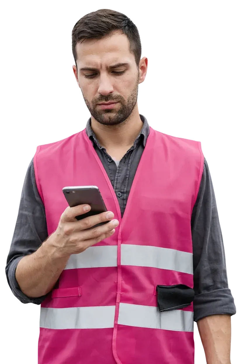 A warehouse team lead in a high visibility vest, reading a message on his phone